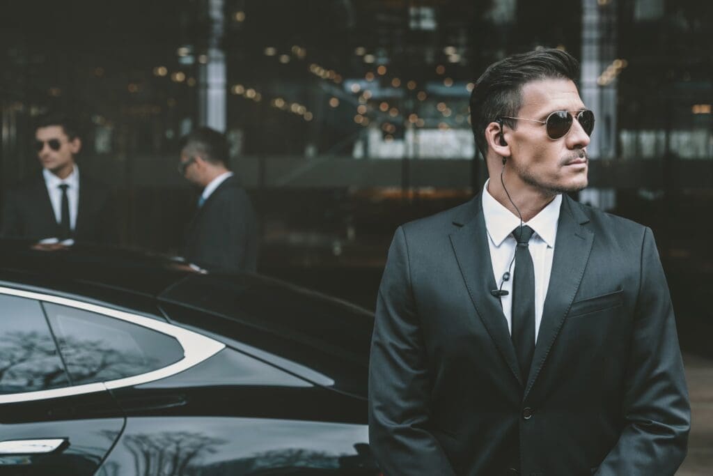 bodyguard standing at businessman car and reviewing territory
