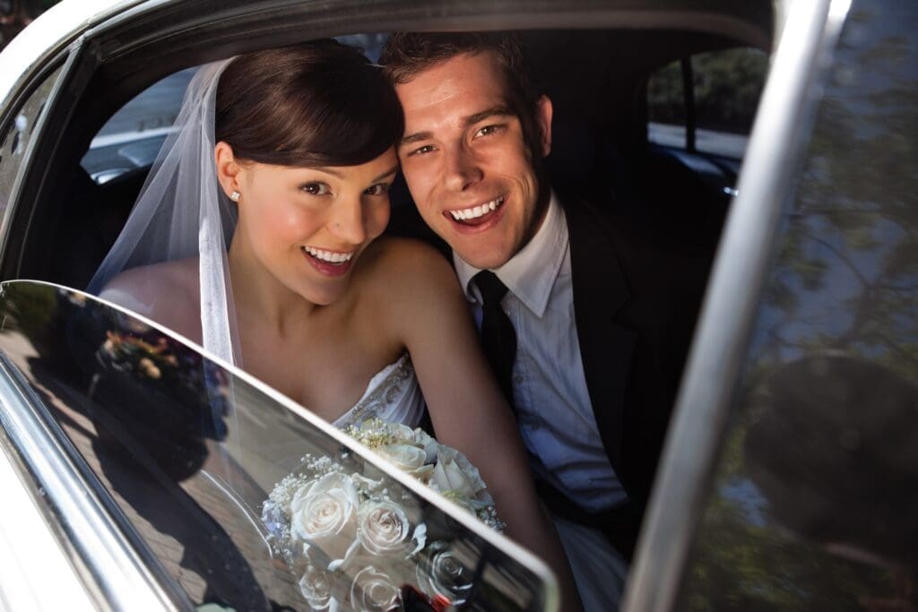 Portrait of happy newly wed couple in car